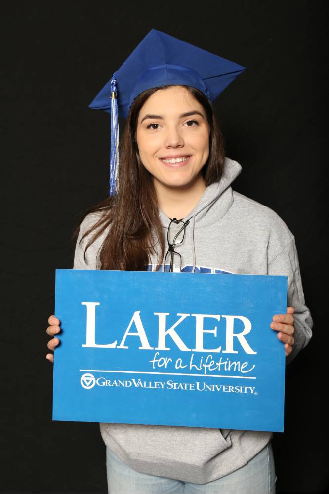 student in grey sweatshirt and blue graduation cap